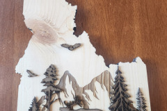 Idaho wall hanging with mountain background and forest scene layered on top